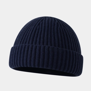 Dettaglio del berretto in maglia blu scuro con trama a coste spesse e bordo arrotolato