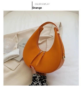 Detail of orange crescent bag with gold zipper and smooth vegan leather texture