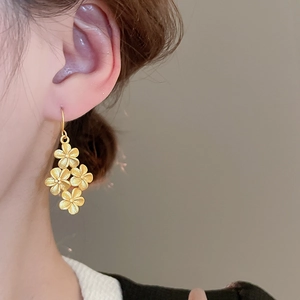 Macro shot of tiered matte gold flower earrings worn to show 3D texture and size