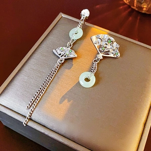 Detail view of asymmetric fan-shaped earrings with jade rings on a jewelry box