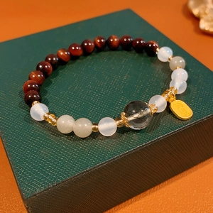 Detail of beaded bracelet with tiger eye stones and golden charm on jewelry box