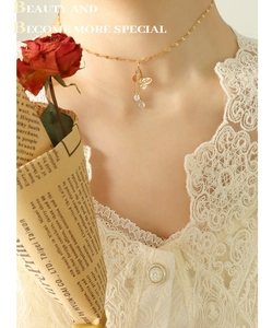 Detail of golden butterfly pendant necklace with zircon tassels on lace outfit