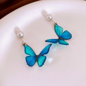 Macro des boucles d'oreilles papillon bleu dégradé avec détails élégants en perles