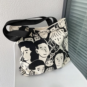 Canvas tote bag detail showing double-sided artistic portrait pattern on a white chair