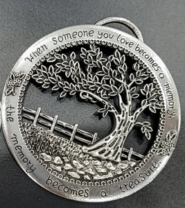Macro shot of silver Tree of Life pendant with engraved memorial poem on metal surface