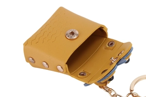 Close-up of open yellow leather owl coin purse with gold rivets and snap button
