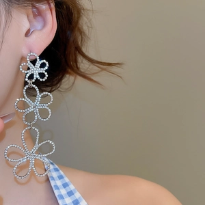 Detail view of silver tassel earrings with flower hollow design and sparkling rhinestones