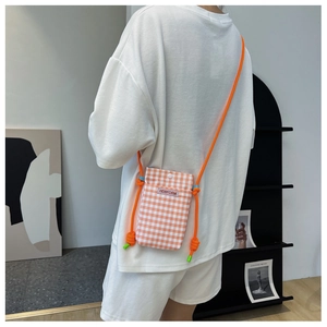 Mini orange checkered crossbody phone bag with knot strap shown on a white casual outfit
