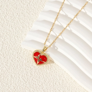 Golden heart necklace with red heartbeat pattern and sparkling crystals on white surface