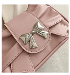 Detail of pink pleated leather bag featuring a silver metal bow accent and textured finish
