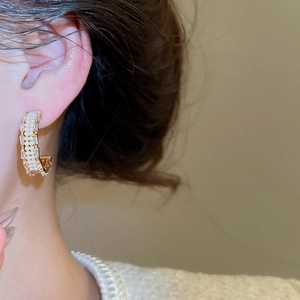 Detail of C-shaped earring featuring pavé pearls and zircons on gold plating