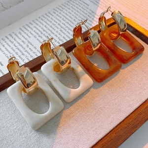 Detail of vintage rectangular resin drop earrings in cream and amber hanging on a tray