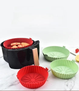 Detail of red and green silicone air fryer liners with heart handles and grooved bottom