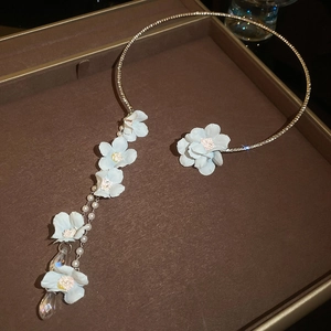 Détail d'un collier floral avec fleur bleu clair et pendentif en cristal en goutte