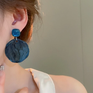 Deep blue marble resin earrings with large round drop and square stud on a model