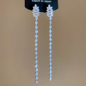 Detail view of silver linear tassel earrings with marquise zircon stones on black card