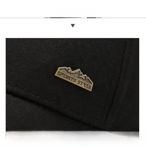 Detailed close-up of a black canvas baseball cap with a vintage bronze sports metal badge