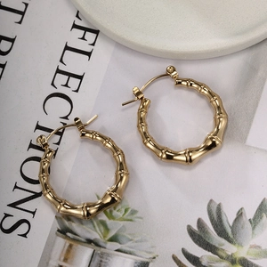 Detailed close-up of golden stainless steel hoop earrings with bamboo texture design