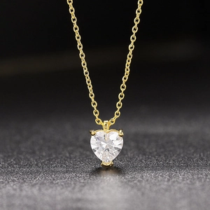 Nahaufnahme eines herzförmigen Edelstein-Anhängers mit goldener Kette auf schwarzem Grund