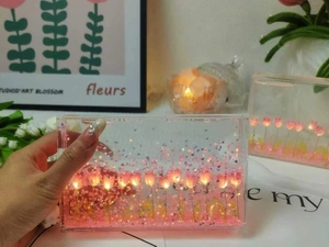 Close-up of glowing pink tulip night light with flowing glitter in a clear acrylic frame