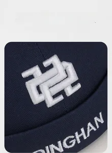 Macro shot of white DINGHAN embroidery and abstract geometric logo on navy blue canvas cap