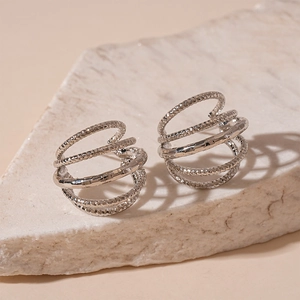 Close-up of silver multilayer spiral earrings with hammer texture on marble background