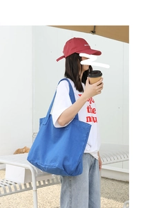 Blue washed canvas tote bag shown on model's shoulder for casual daily style