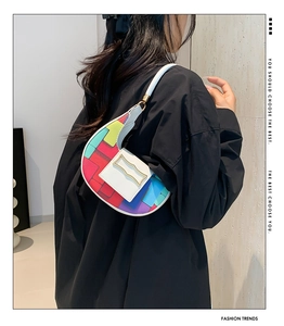 Detail of color-block crescent bag with matte leather finish and golden clasp on model