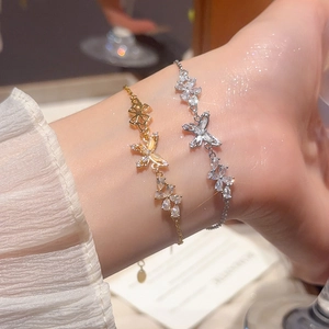 Close-up of 18k gold and silver butterfly floral bracelets with sparkling zircon stones