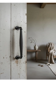 Detail of vintage cast iron door handle with black sandblasted texture on rustic wood