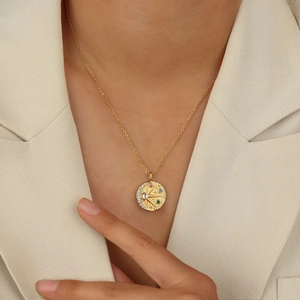Collier à pendentif pièce dorée avec motifs soleil et lune porté par un mannequin chic