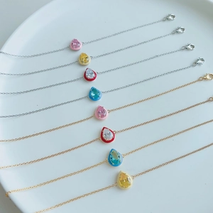 Detail of S925 silver and gold bracelets with colorful enamel teardrop charms on a tray