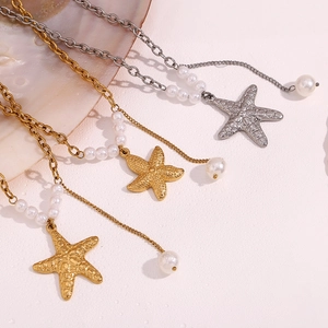 Detailed view of 18K gold and silver starfish necklaces with pearls on shell background