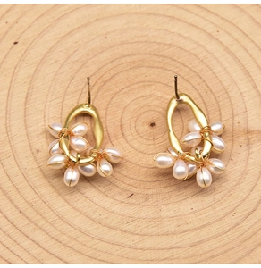 Macro shot of gold wire-wrapped pearl earrings on a natural wood surface detail