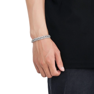 Silver 10mm cuban link bracelet with zircons worn by a male model on a white background