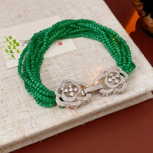 Detail view of multi-strand green beaded bracelet with a sparkling silver flower clasp