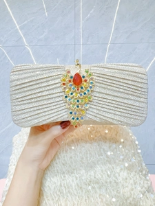 Detail of silver evening clutch with peacock-shaped crystal buckle and a red teardrop gem