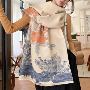 Detail of beige scarf with orange floral patterns, blue landscape art and fringe edges