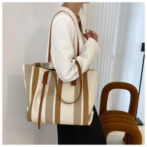 Detailed texture of the striped canvas tote bag with brown leather shoulder straps