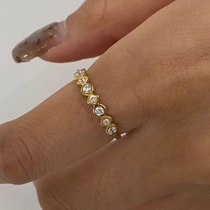 Close-up of a gold-plated stainless steel ring with pavé diamonds on a model's finger
