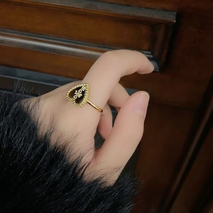 Nahaufnahme eines goldenen Herzrings mit Girl-Schriftzug und Perlenrand am Finger