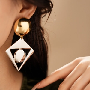 Close-up of model wearing gold spherical and silver geometric drop earrings