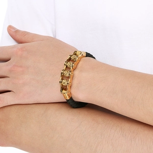 Detail of men's black braided bracelet with golden skull and chain metal buckle on wrist