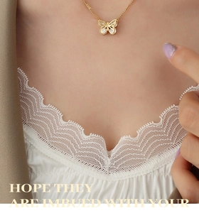 Close-up of a gold butterfly pendant necklace with zircon stones on a model's collarbone