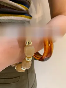 Detail of amber tortoiseshell acrylic bangle paired with beige resin beaded bracelet set