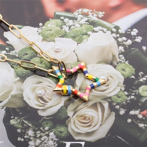 Gold chain necklace with a colorful striped five-point star pendant on floral background