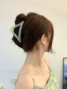 Detail of light green triangular matte hair claw clip and elegant pearl necklace on model