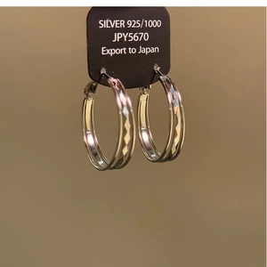 Close-up of S925 sterling silver hoop earrings featuring a polished metallic finish