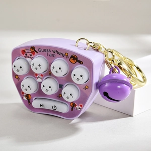 Detail of a purple mini whack-a-mole toy keychain with a bell on a display block