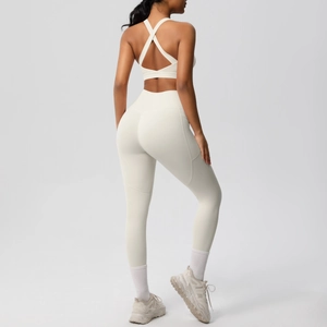 Detail of cream white yoga set featuring cross-back sports bra and high-waist side pocket leggings